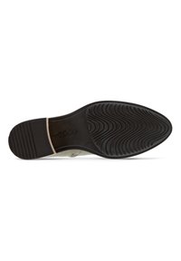 Suela de zapato de goma negra con patrones texturizados y estrías. Diseño beige suave que incluye un corte elegante cerca del área del talón.