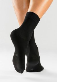 Schwarze Baumwollknöchelsocken mit gerippten Bündchen, glatter Textur und kleinen weißen Akzentdetails auf den Sohlen.