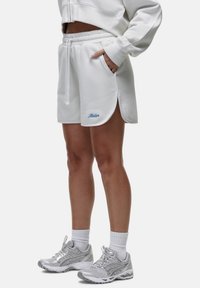 Shorts bianchi in misto cotone con tasche laterali, vita a coste e orlo curvo. Presenta un logo ricamato blu sulla gamba sinistra.