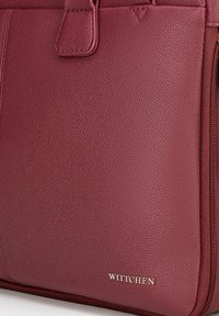 Bordeaux leren handtas met een gestructureerd oppervlak, rits en een gouden "WITTCHEN" logo op de voorkant. Compact ontwerp met stevige hardware.
