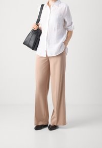 Witte linnen overhemd met knopen, beige wijde broek, zwarte leren tas en zwarte flats. Eenvoudig ontwerp met een relaxte pasvorm.