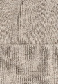 Strikket beige hue lavet af blødt materiale, med ribbet manchet og struktureret mønster over hele huen. Let meleret udseende.