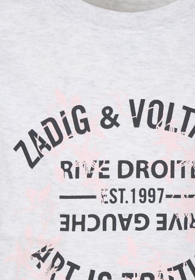 T-shirt en coton gris avec du texte imprimé en noir et rose clair, y compris le nom de la marque et des éléments floraux décoratifs.