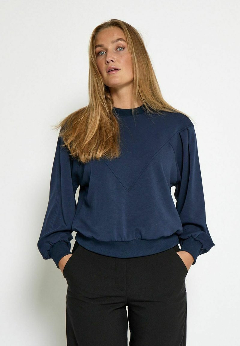 Navy blue sweatshirt with long sleeves, featuring a V-shaped design at the front and gathered cuffs. Made of soft material, relaxed fit.
