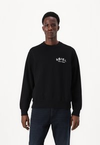 Sort sweatshirt med rund hals, ribbede ærmer og kant. Har hvid broderet tekst og en enkel grafik på venstre brystområde.