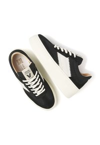 Black and white sneakers featuring a suede and mesh design, with a thick white sole and contrasting zigzag pattern on the side.