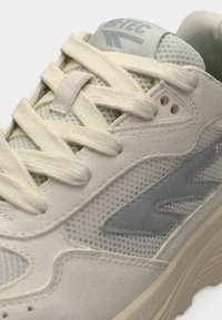 Ανοιχτό γκρι αθλητικό παπούτσι με υλικά δίχτυ και σουέντ, επίπεδα κορδόνια, λεπτό λογότυπο και υφασμένα στοιχεία στο πλάι για καλύτερη πρόσφυση.