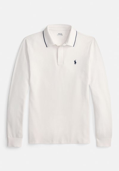 Balta ar garām piedurknēm polo krekls ar melnu apmalējumu apkaklī un nelielu melnu izšūtu logotipu uz kreisās krūts.