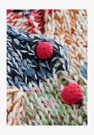 Többszínű kötött anyag vastag fonalakkal kék, rózsaszín és bézs árnyalatokban, texturált, kerek piros bojttal díszítve.