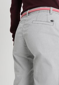 Jasnoszare bawełniane spodnie o gładkiej fakturze, z różowym paskiem i tylną kieszenią z czarnym logo.