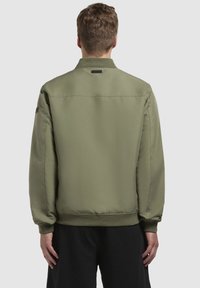 Olivgrüne Bomberjacke aus glattem Material, mit geripptem Kragen und Bündchen, elastischem Taillenbund und einem kleinen Markenlabel auf der Rückseite.