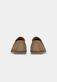 Helle Wildleder-Loafer mit niedrigem Profil, weicher Textur, runder Zehenform und minimalem Nähdetail, ausgestattet mit einer flachen Gummisohle für Komfort.