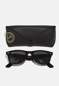 Ray-Ban Wayfarer prillid tumedate läätsedega, kilpkonnakilbi plastraamiga. Komplektil on must tekstuuriga nahk Kate kuldse logoga.