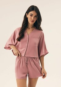 Różowy satynowy zestaw odzieży domowej z button-upem, krótkim rękawem i kieszonką oraz szortami z elastycznym pasem dla swobodnego dopasowania.
