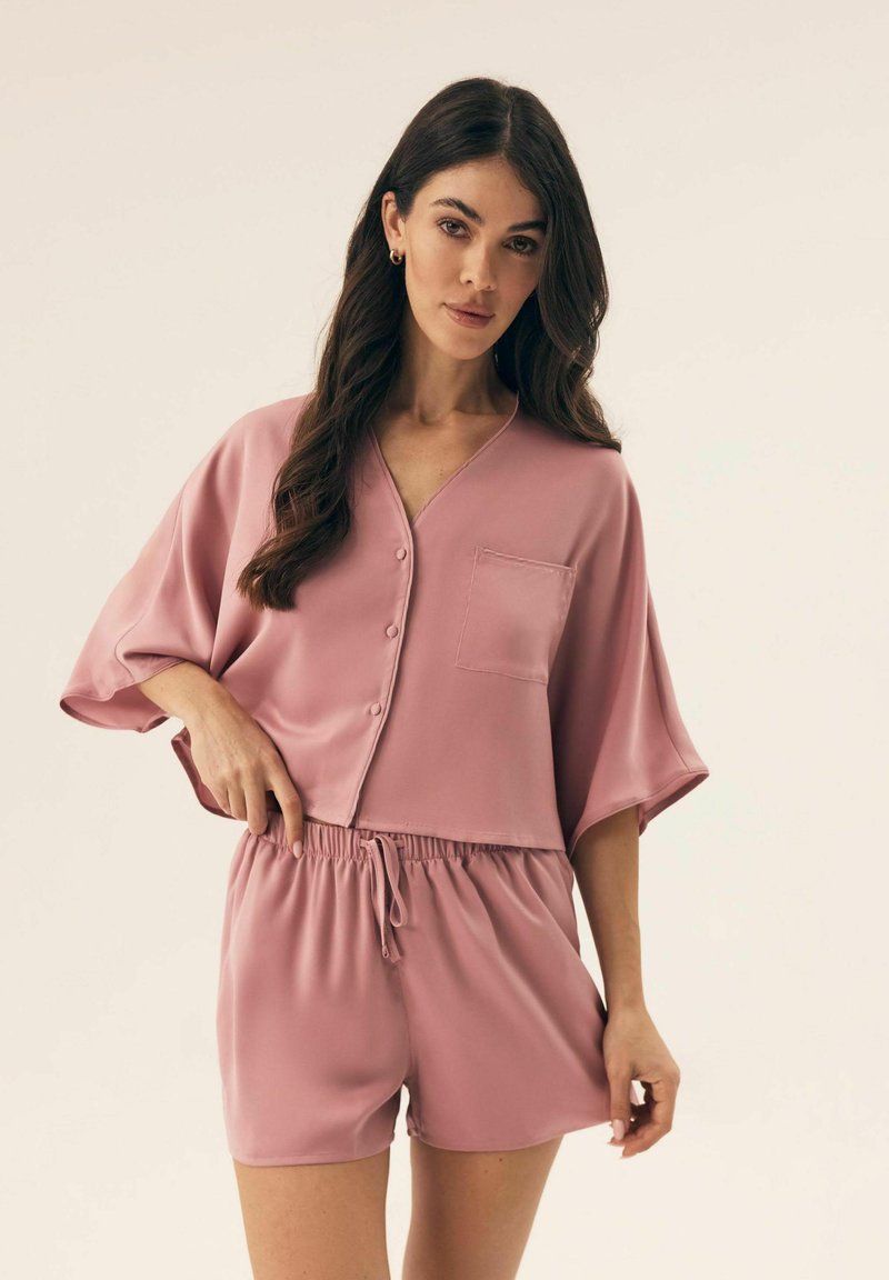 Różowy satynowy zestaw odzieży domowej z button-upem, krótkim rękawem i kieszonką oraz szortami z elastycznym pasem dla swobodnego dopasowania.