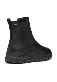 Botines negros de cuero con paneles elásticos en los lados y suela de goma texturizada. Presenta un tacón bajo y un acabado suave.