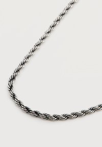 Ασημένιο κολιέ με στριφτή αλυσίδα σε σχήμα σχοινιού με εναλλασσόμενες ελαφριές και σκούρες μεταλλικές φλέβες σε απλό λευκό φόντο.