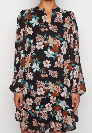 Langærmet sort kjole med blomster i pink, brun og blågrøn, med V-formet udskæring og lagdelt nederdel.