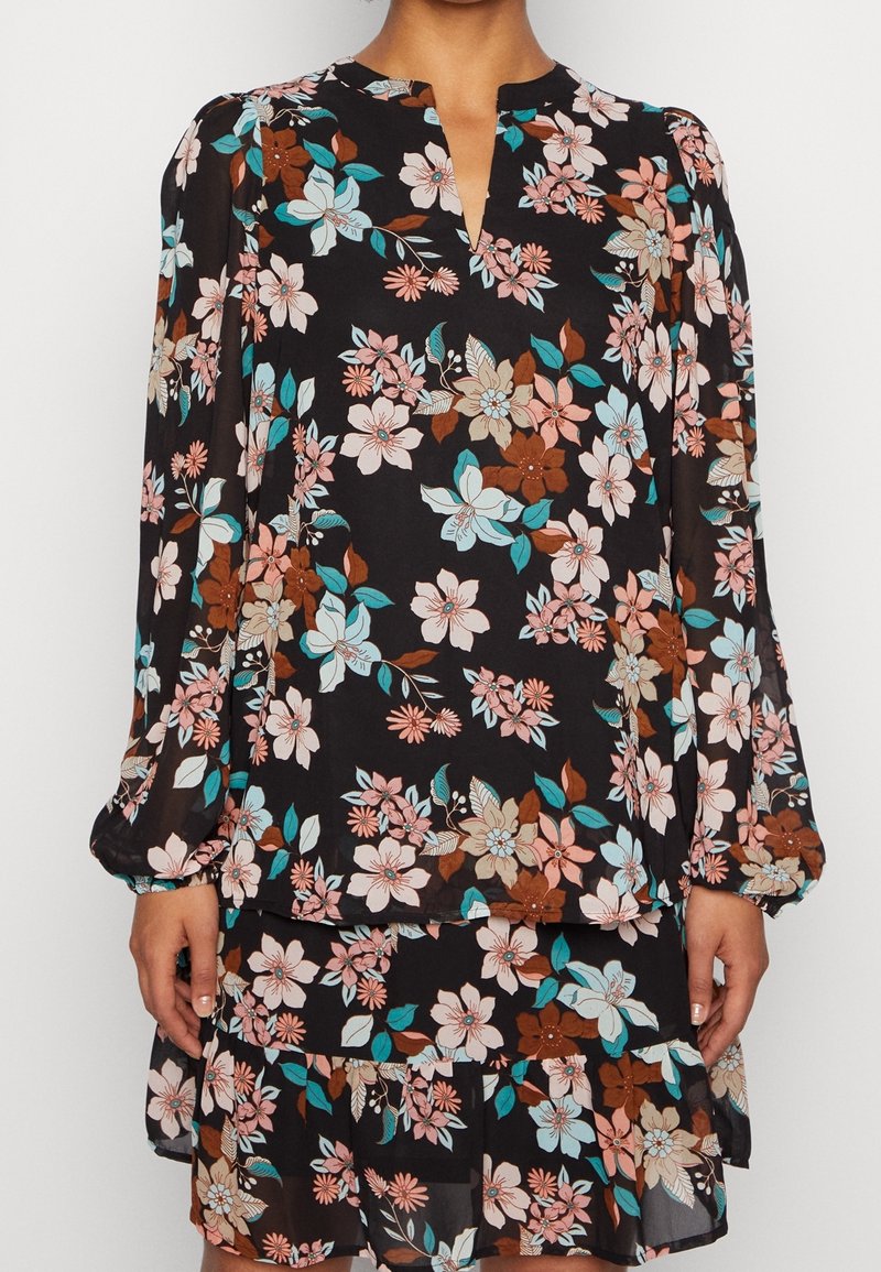 Robe noire à manches longues à fleurs roses, marron et bleu-vert, avec un décolleté en V et une jupe à volants.