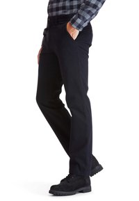 Fekete, slim-fit nadrág szőtt anyagból, oldalsó zsebekkel és sima felülettel, fekete strapabíró csizmával párosítva.