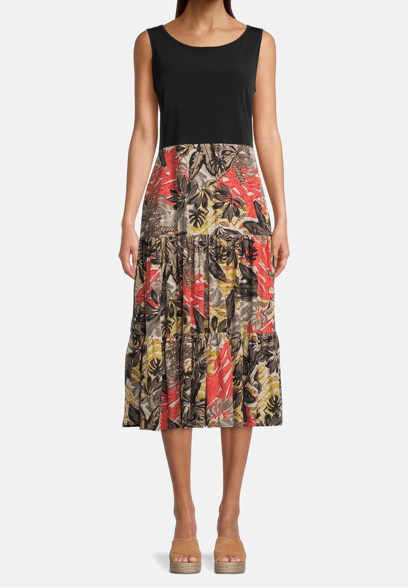 Svart tanktopp med en knälång, lager-på-lager blommönstrad kjol i röd, gul och grön. Har tropiska bladmönster och en avslappnad passform.