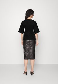 Top preto estruturado com mangas curtas e costas elásticas, emparelhado com uma saia lápis de couro preta ajustada. Textura suave e design elegante.