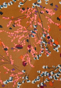 Tecido castanho com um padrão floral, apresentando aglomerados de tons de rosa, vermelho, branco e preto, sobre um fundo texturizado.