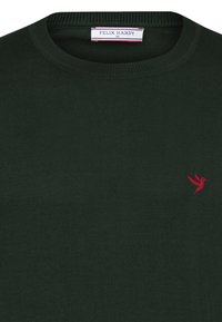 Tume roheline kudum, millel on ümar kaelus ja väike punane kolibri logo vasakul rinnal. Pehme tekstuur, vabamood.