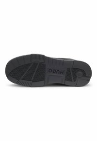 Suola di sneaker in gomma nera con motivi testurizzati, caratterizzata da creste e un prominente logo "HUGO" sulla suola intermedia. Design resistente per una maggiore aderenza.
