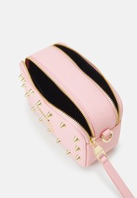 Różowa torebka na suwak ze złotymi dodatkami, z metalowymi ćwiekami po jednej stronie. Wnętrze wyłożone czarną podszewką. Kompaktowy, prostokątny kształt.