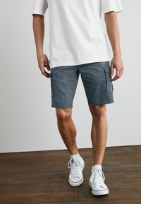 Graue Cargo-Shorts mit zwei Seitentaschen, geradem Schnitt, aus einem Baumwollmischgewebe und einer Länge, die bis zur Mitte des Oberschenkels reicht.