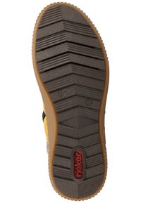 Semelle de chaussure en caoutchouc avec un motif texturé. Présente un bord contrastant marron, un logo en relief et un marquage de taille. Couleur principalement gris foncé.