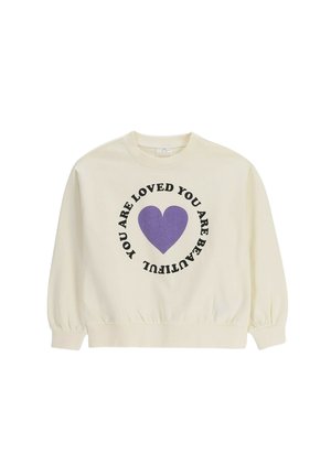 Bluza kremowego koloru z fioletowym sercem na środku i czarnym tekstem wokół, na którym napisano „Jesteś piękna Jesteś kochana.”