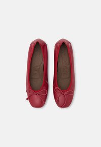 Ballerines en cuir rouge à bout arrondi, avec un nœud décoratif à l'avant et une semelle intérieure rembourrée affichant une texture lisse.