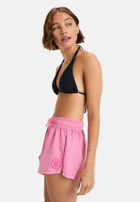 Schwarzer dreieckiger Bikinibra und pinke Badehose mit elastischem Bund und Logo-Patch, die einen lockeren Sitz und eine glatte Textur bietet.
