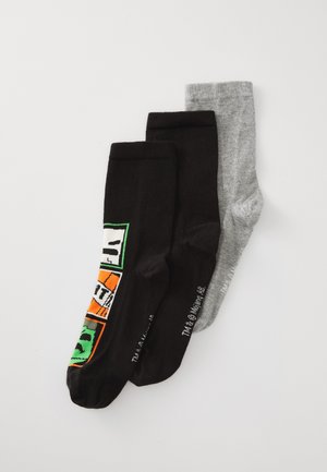 Drei Paare gefaltener Knöchelsocken; zwei schwarze mit bunten grafischen Blöcken, eine schlichte hellgraue, auf einem weißen Hintergrund.