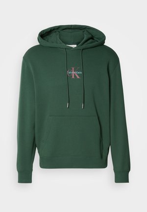 Sudadera de mezcla de algodón verde con bolsillo frontal, puños acanalados y capucha con cordón. Logo decorativo de Calvin Klein en colores contrastantes.