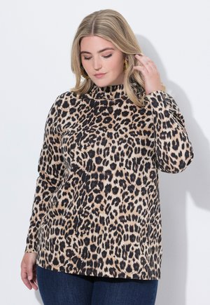 Top de manga larga con estampado de leopardo en beige y negro, con cuello alto y textura suave, combinado con jeans azul oscuro.