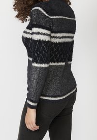 Marinblå och grå stickad tröja med texturerad yta, med horisontella ränder och diamantmönster i ljusgrått och vita accenter.