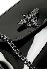 Borsa a tracolla in pelle verniciata nera con catena argentata e un emblema decorativo a forma di ape sul davanti. Finitura lucida e design elegante.