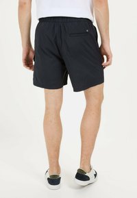 Donkerblauwe zwemshorts met een elastische tailleband, zijzakken en een achterzak met rits. Lichtgewicht, sneldrogend materiaal met een zachte textuur.