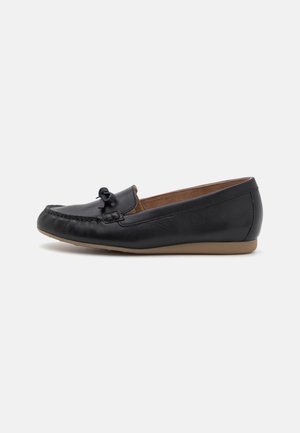 Black leather loafers with a rounded toe, featuring a bow detail on the vamp and a flexible tan rubber sole. Smooth texture and minimalist design.