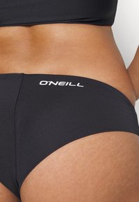 Musta bikinitarha, valmistettu sileästä kankaasta. Ominaisuuksina matala vyötäröleikkaus ja valkoinen O'Neill-logo sivussa. Tarjoaa minimalistisen muotoilun.