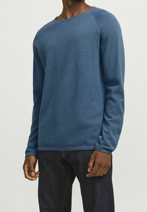 Blauer Pullover mit langen Ärmeln aus strukturiertem Strickmaterial, mit Rundhalsausschnitt und gerippten Bündchen, kombiniert mit dunklen Jeans.