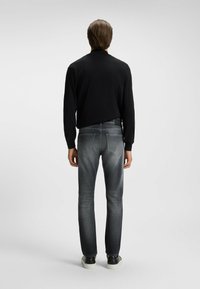 Maglietta nera a maniche lunghe, jeans denim grigi con effetto sbiadito e sneakers nere. Design semplice, taglio dritto e dettagli minimi.