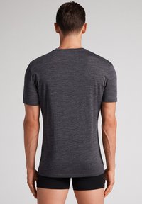 Szara krótka koszulka z krótkim rękawem, wykonana z lekkiego, teksturowanego materiału, z okrągłym dekoltem i dopasowanym krojem, pokazana z tyłu.