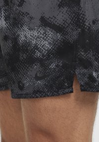 Juodi sportiniai šortai su tekstūruota, abstrakčia spauda. Turintys subtilų Nike logotipą. Dizainas turi šoninius plyšius mobilumui.