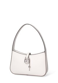 Sac à main en cuir blanc avec une poignée incurvée, orné d'un pendentif logo circulaire et d'un petit pendentif en forme de clé, bordé d'une finition noire.