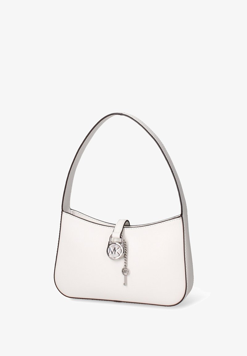 Sac à main en cuir blanc avec une poignée incurvée, orné d'un pendentif logo circulaire et d'un petit pendentif en forme de clé, bordé d'une finition noire.