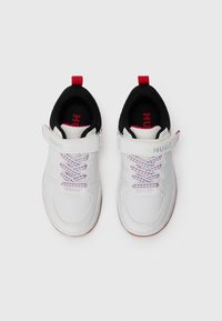 Baskets blanches avec un contour noir, une sangle Velcro et des lacets multicolores. Le nom de la marque "HUGO" est imprimé sur la sangle. Semelle en caoutchouc.